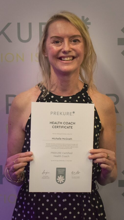 Michelle holding her PREKURE Health Coach Certificate